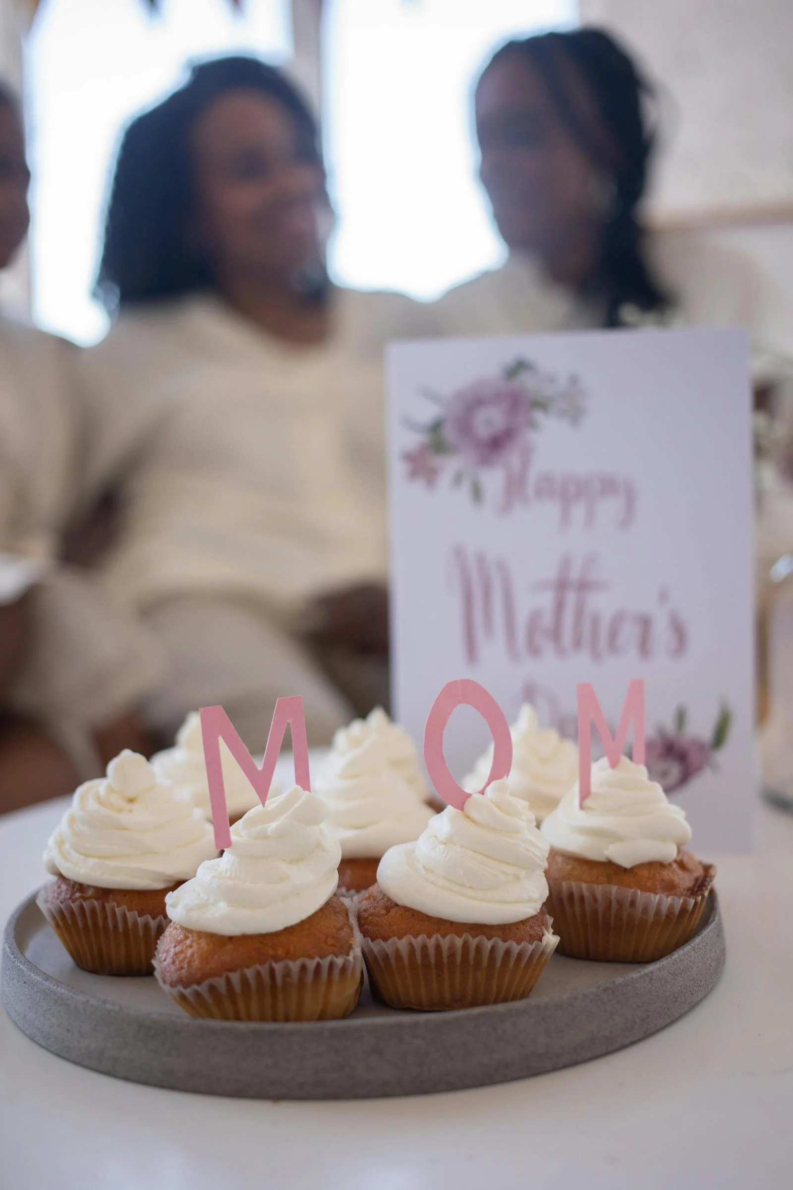 Handwritten happy Mother's Day card with flowers on a wooden table