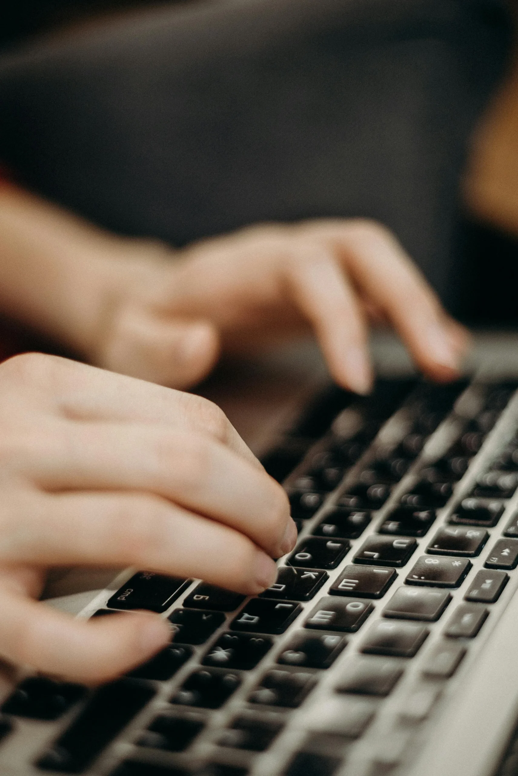 Hands typing on a laptop keyboard, using AI-powered productivity tools